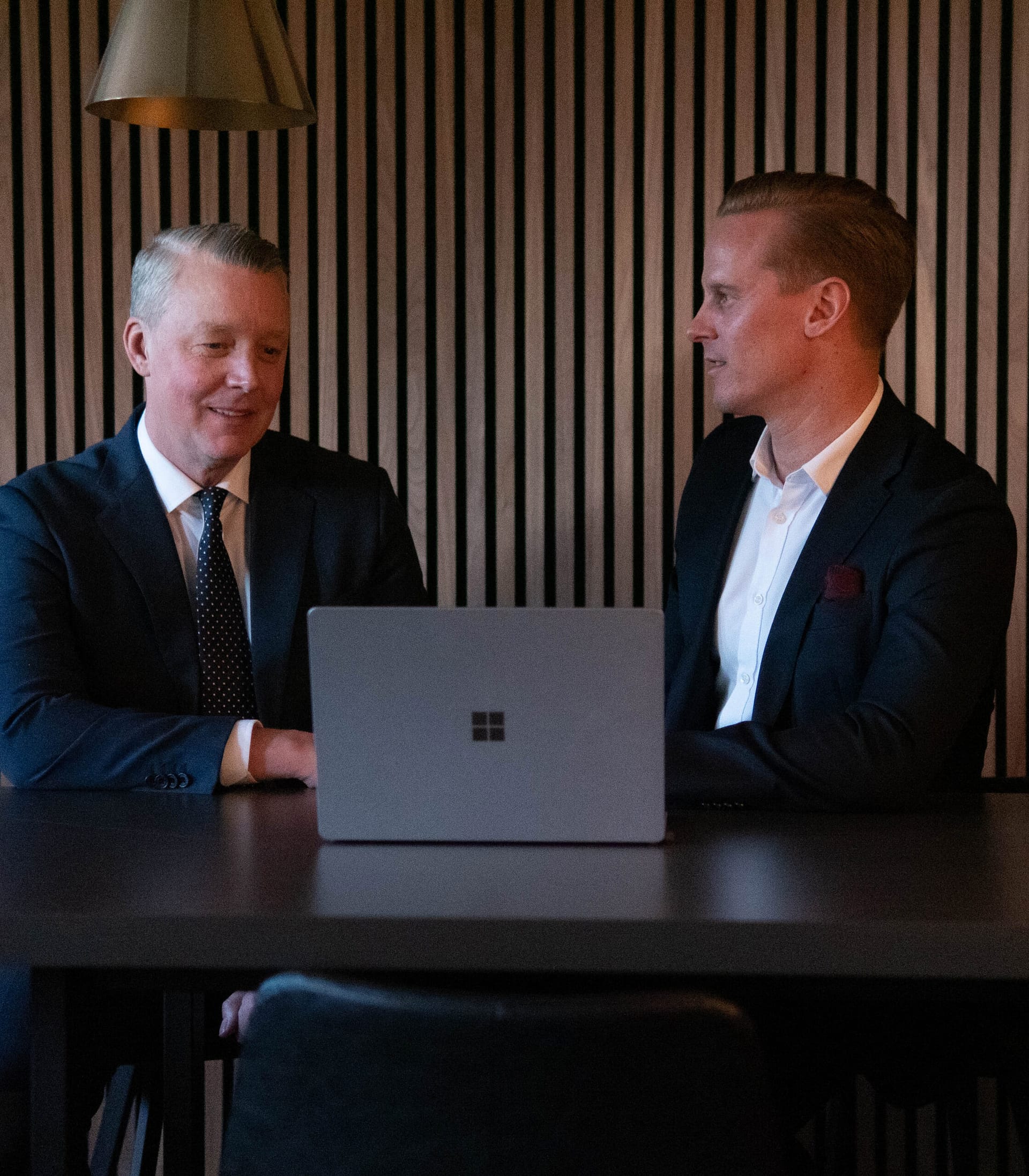 Två välklädda män med dator på modernt kontor